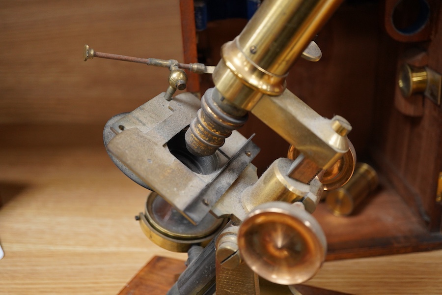 A mid 19th century brass compound monocular microscope, by J & C Robbins, 9, Bartholomew Close, London, with accessories and various slides, raised on a wooden base, the case 25cm high
